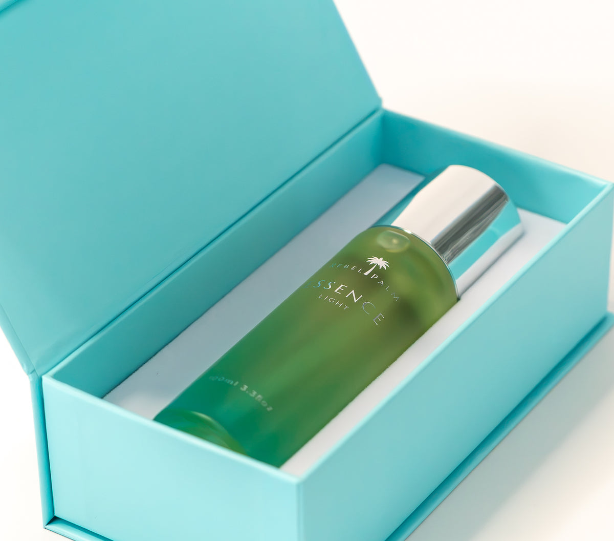 Rebel Palm Essence Light Body Oil nestled in open teal luxury gift box, 100ml