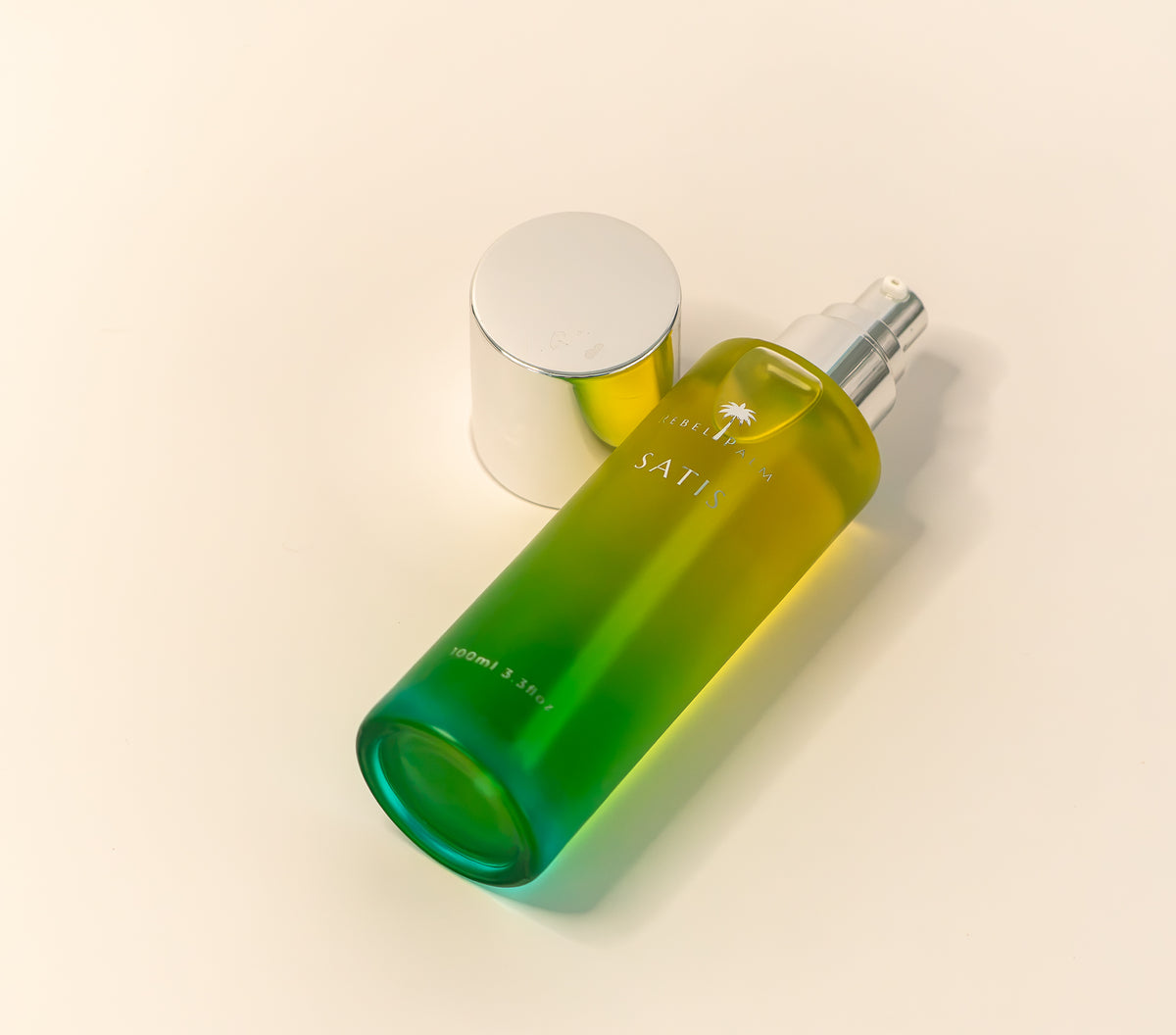 Rebel Palm Satis Post-Shower Body Oil 100ml glass bottle lying on its side with silver cap beside it