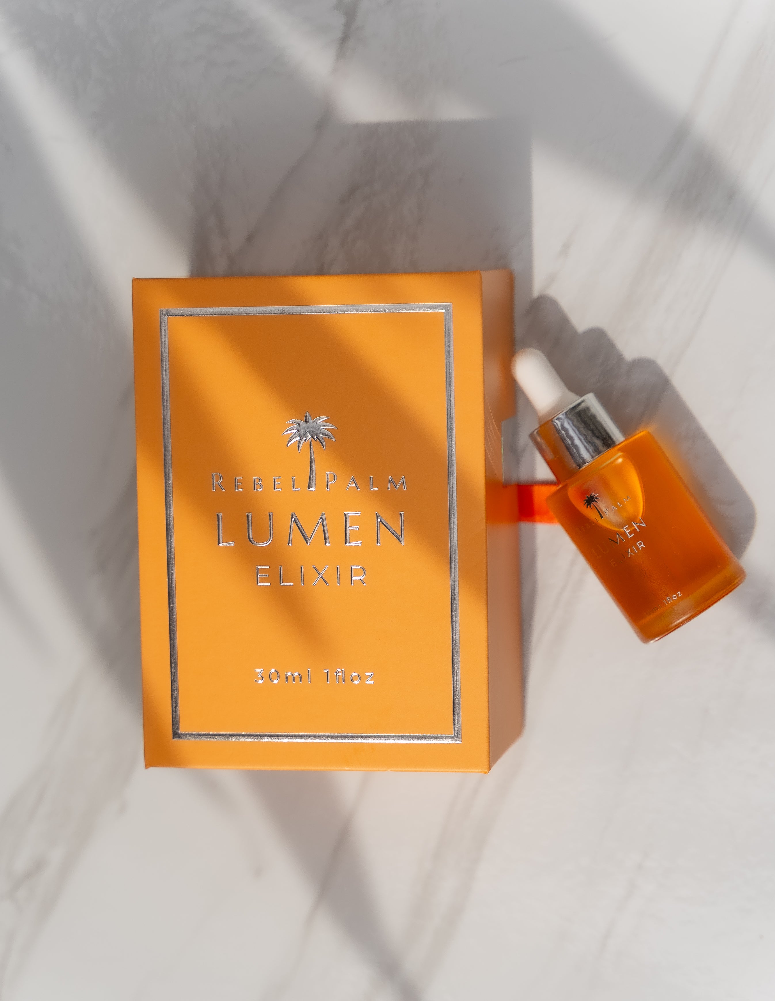 Orange Lumen Elixir bottle and box on a light background
