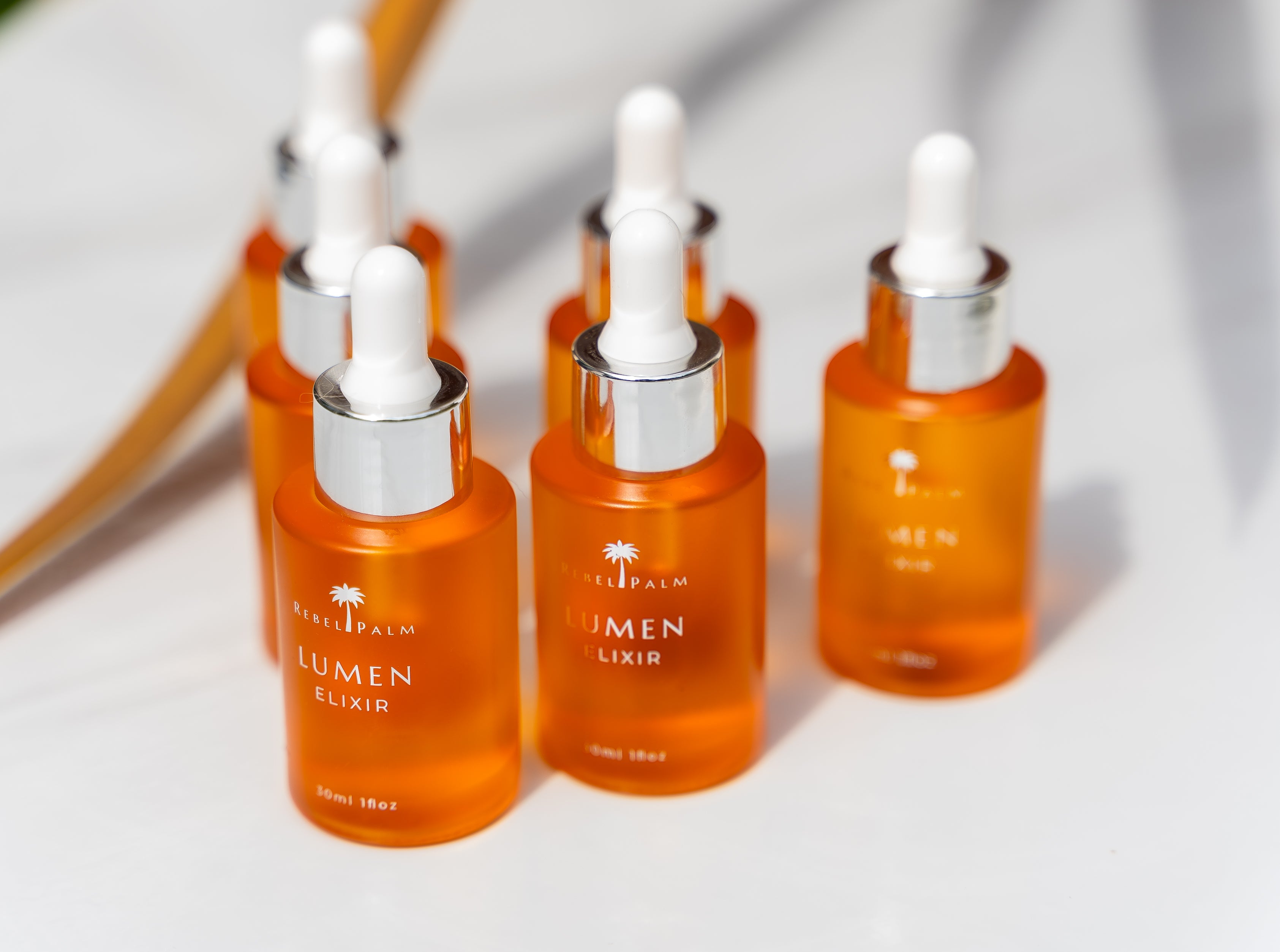 Orange serum bottles with white caps on a light background