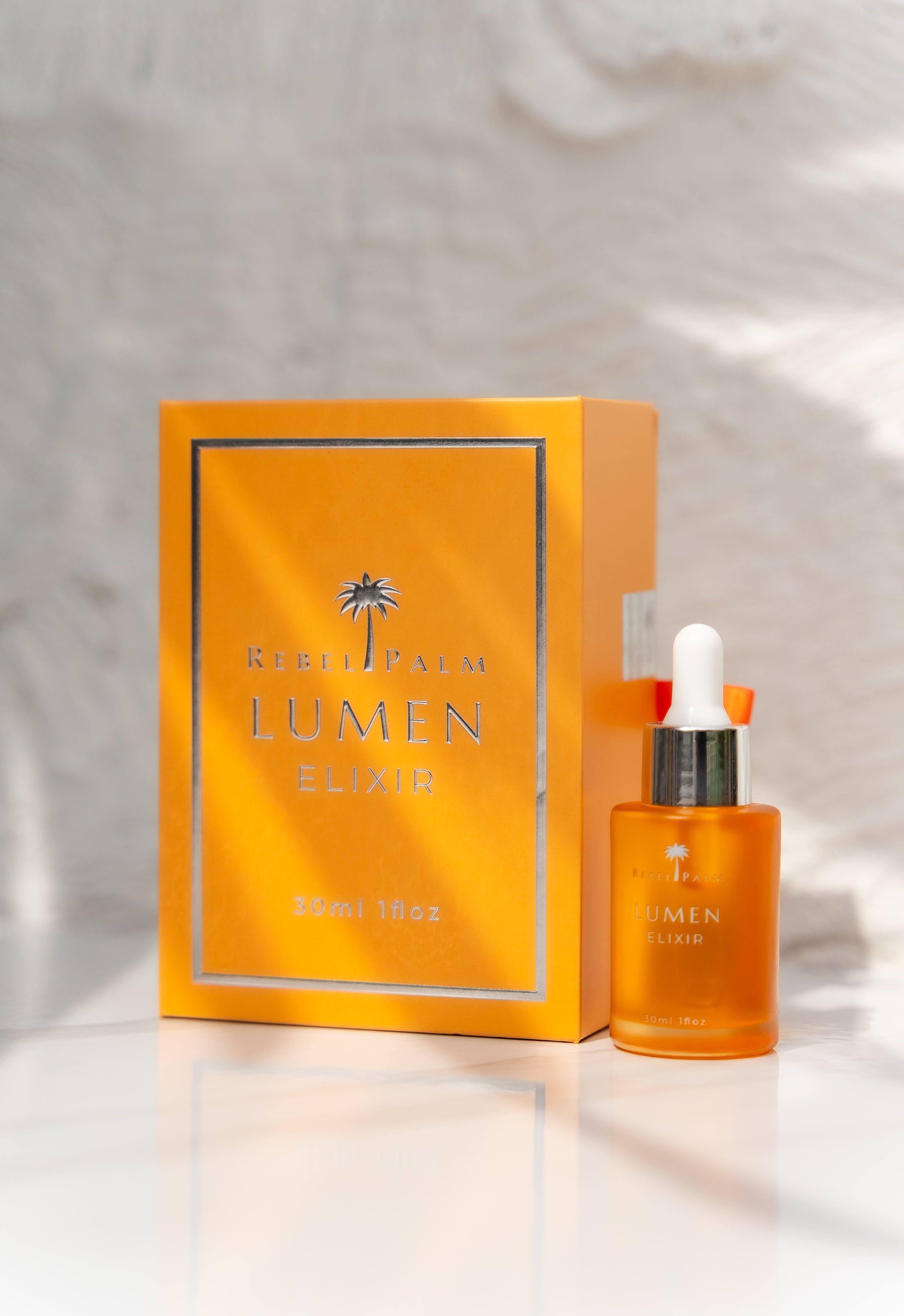 Orange bottle and box of Lumen Elixir on a light background